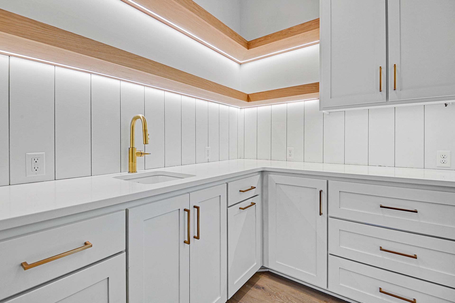 A kitchen with white cabinets , white counter tops , and a sink.