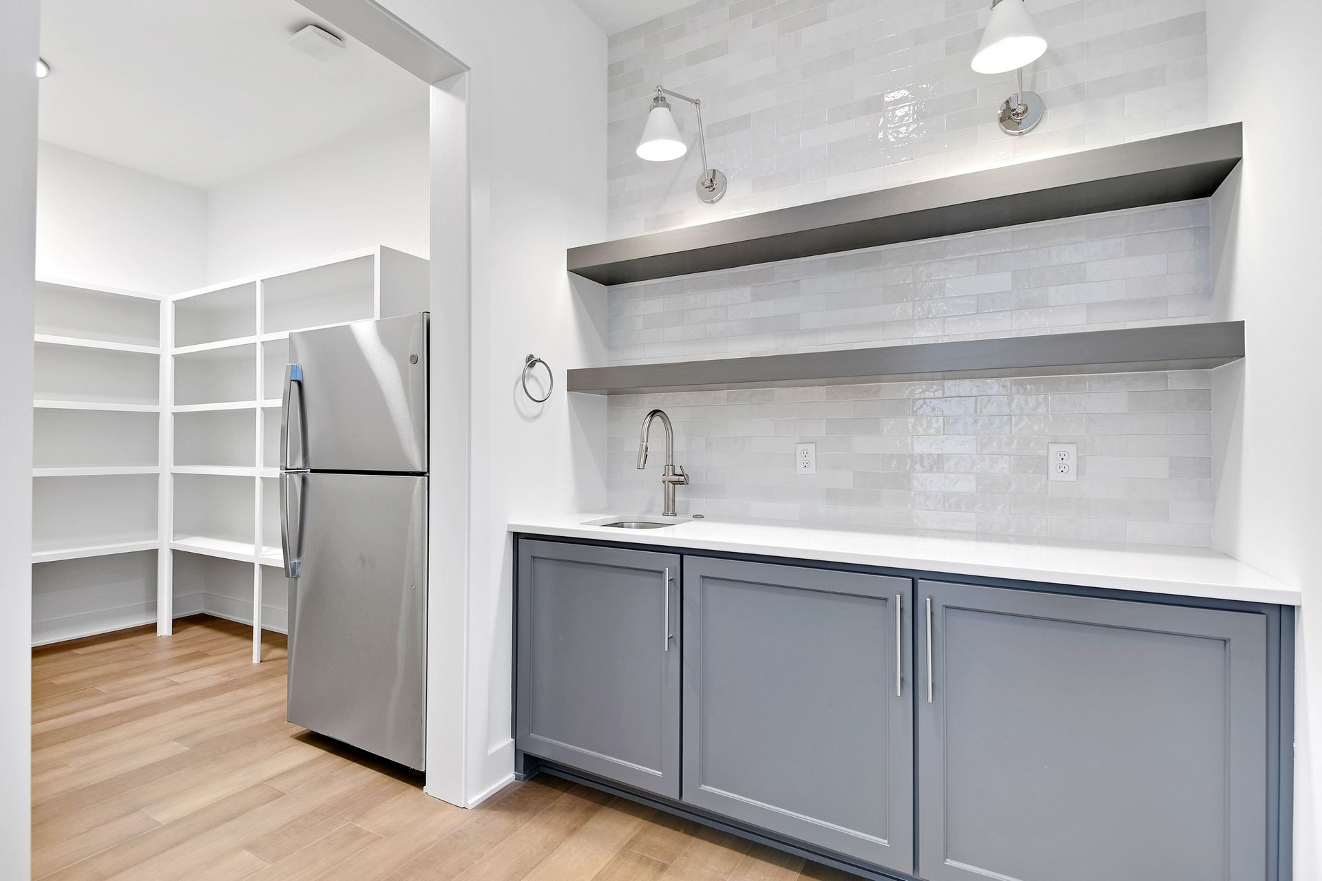 A kitchen with a refrigerator , sink , and shelves.