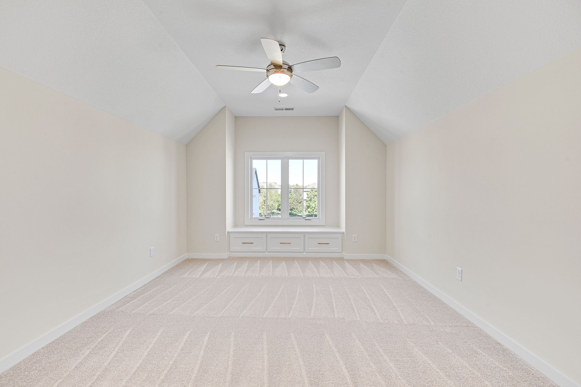 An empty room with a ceiling fan and a window.