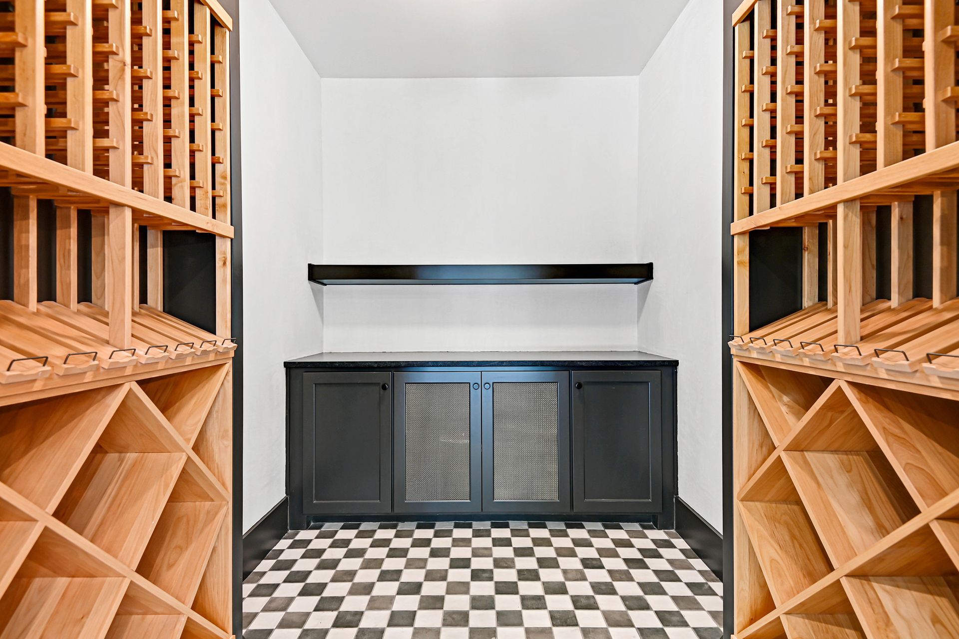 A wine cellar with wooden shelves and a checkered floor.