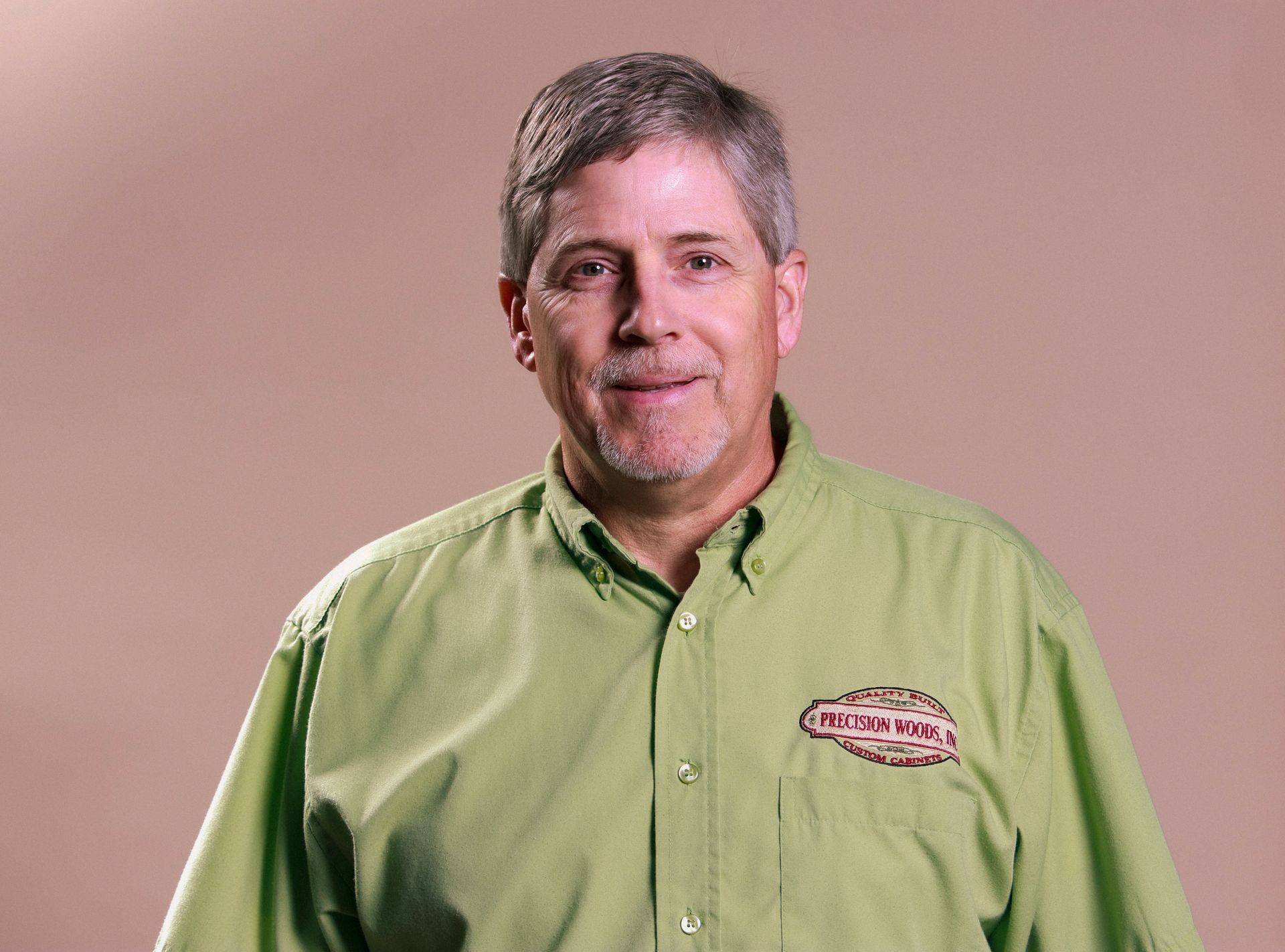 A man in a green shirt is smiling for the camera.