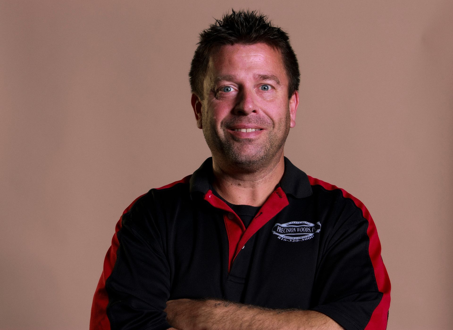 A man with his arms crossed is wearing a black and red shirt