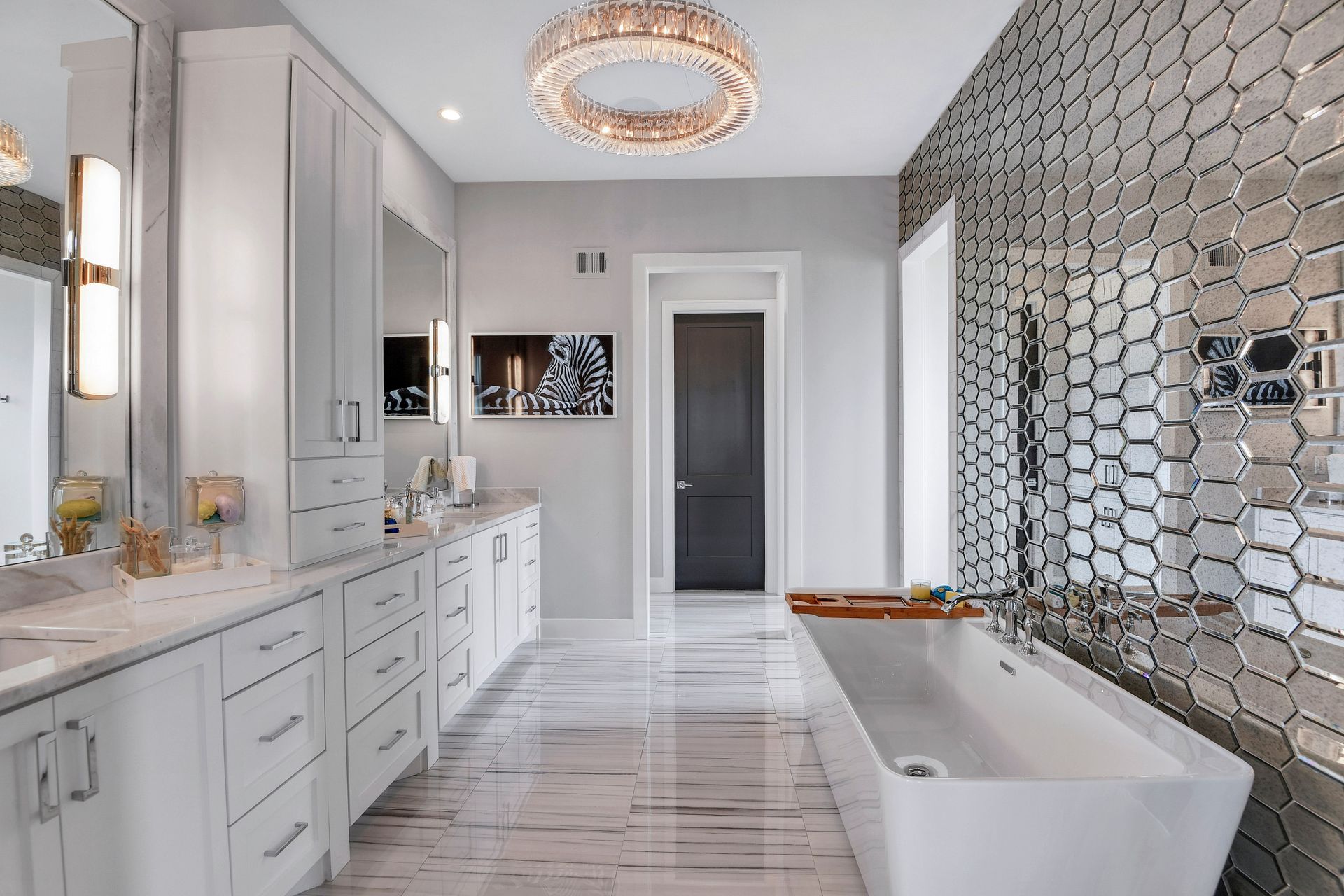 A bathroom with a bathtub , sinks , mirrors and a chandelier.