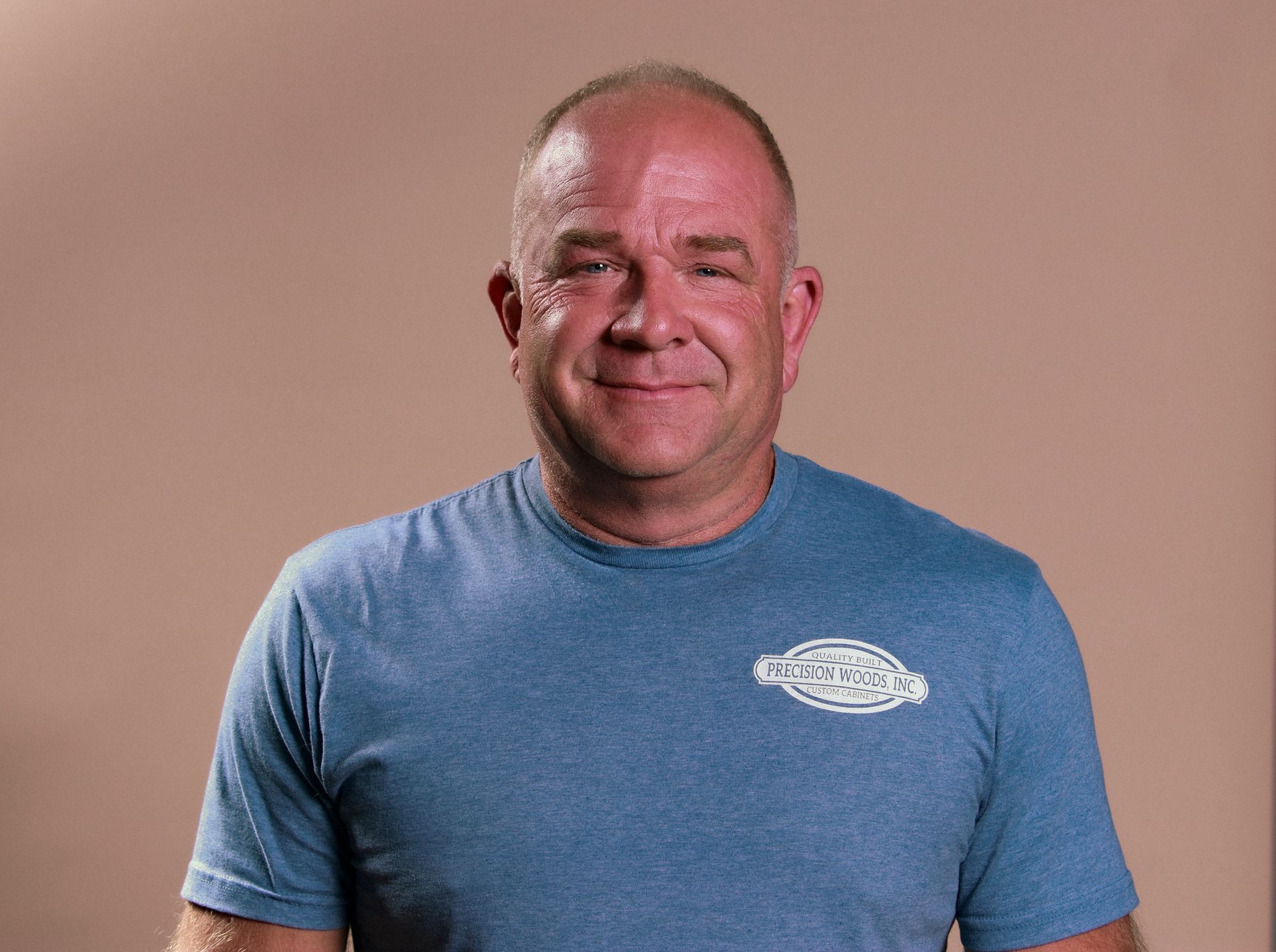 A man in a blue shirt is smiling and looking at the camera.