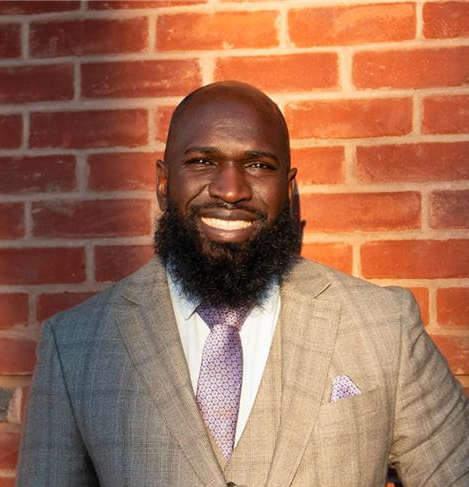 Woman with long blonde hair, smiling at camera, wearing a beige sweater.