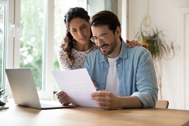 Happy affectionate young family couple reading paper correspondence