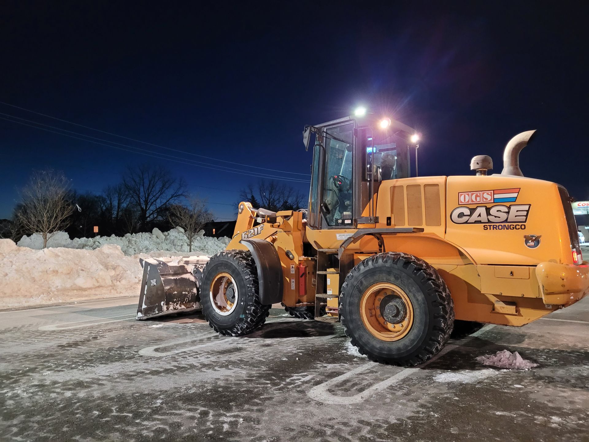 heavy equipment moving snow in large parking lot