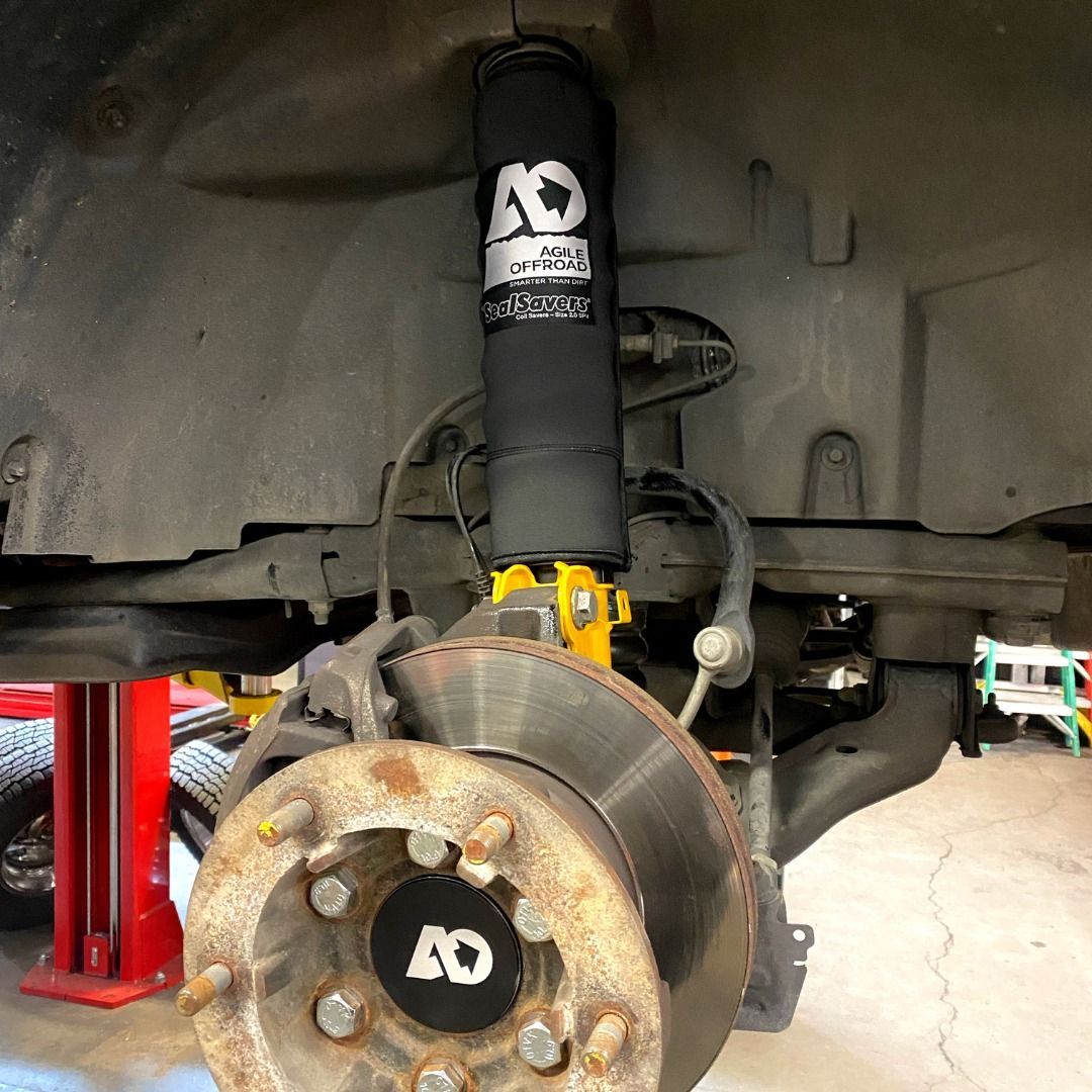 A vehicle wheel hub and suspension strut with a black protective cover branded with an 