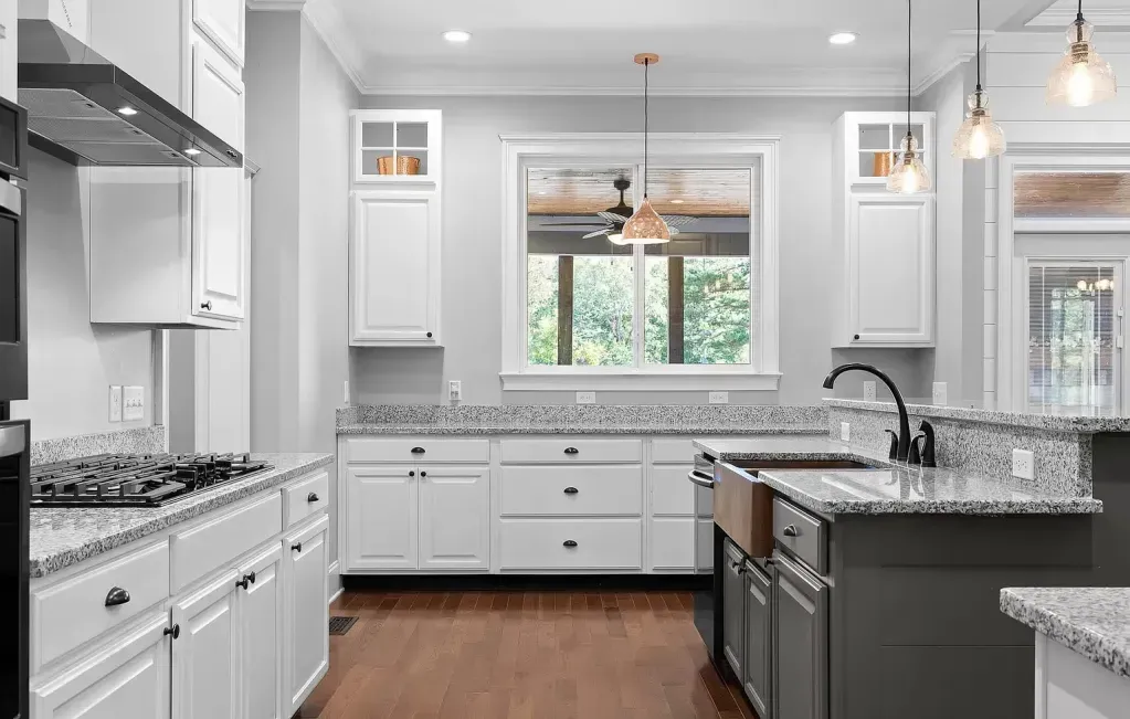 A kitchen with white cabinets , granite counter tops , and a sink.