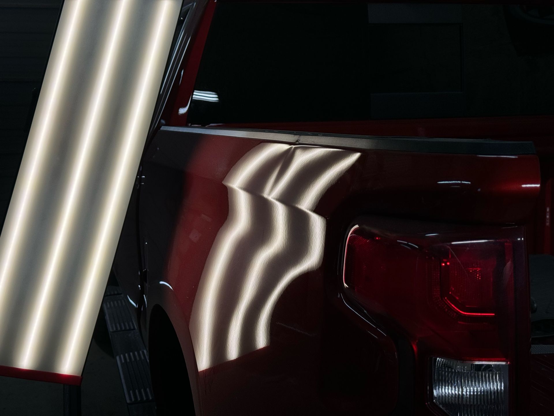 A close up of a red truck with dents on it