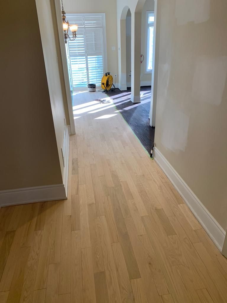 A hallway with hardwood floors leading to a living room.