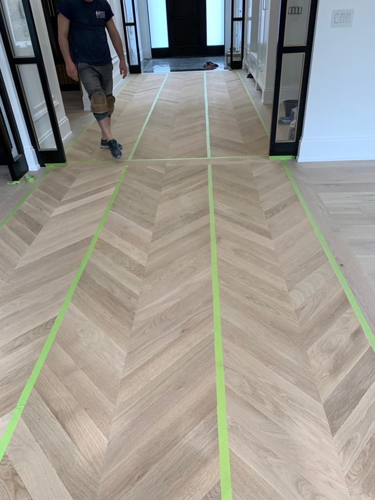 a man walking on a wooden floor with a chevron pattern