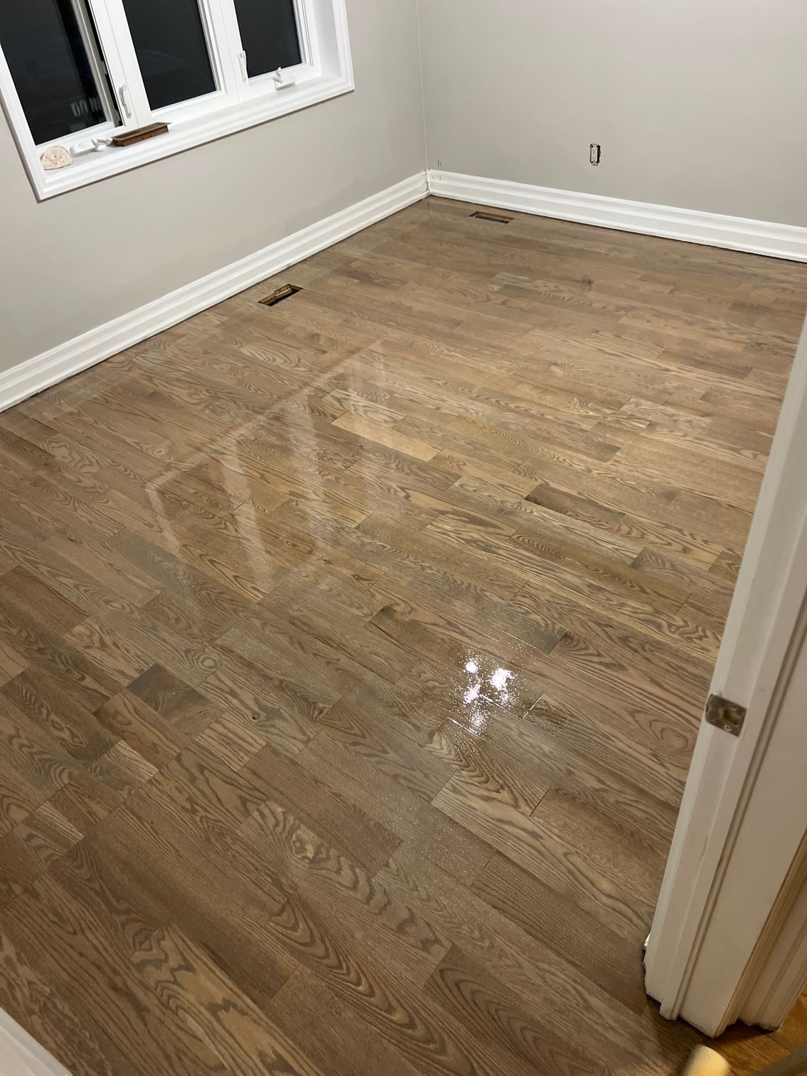 A room with hardwood floors and a window.