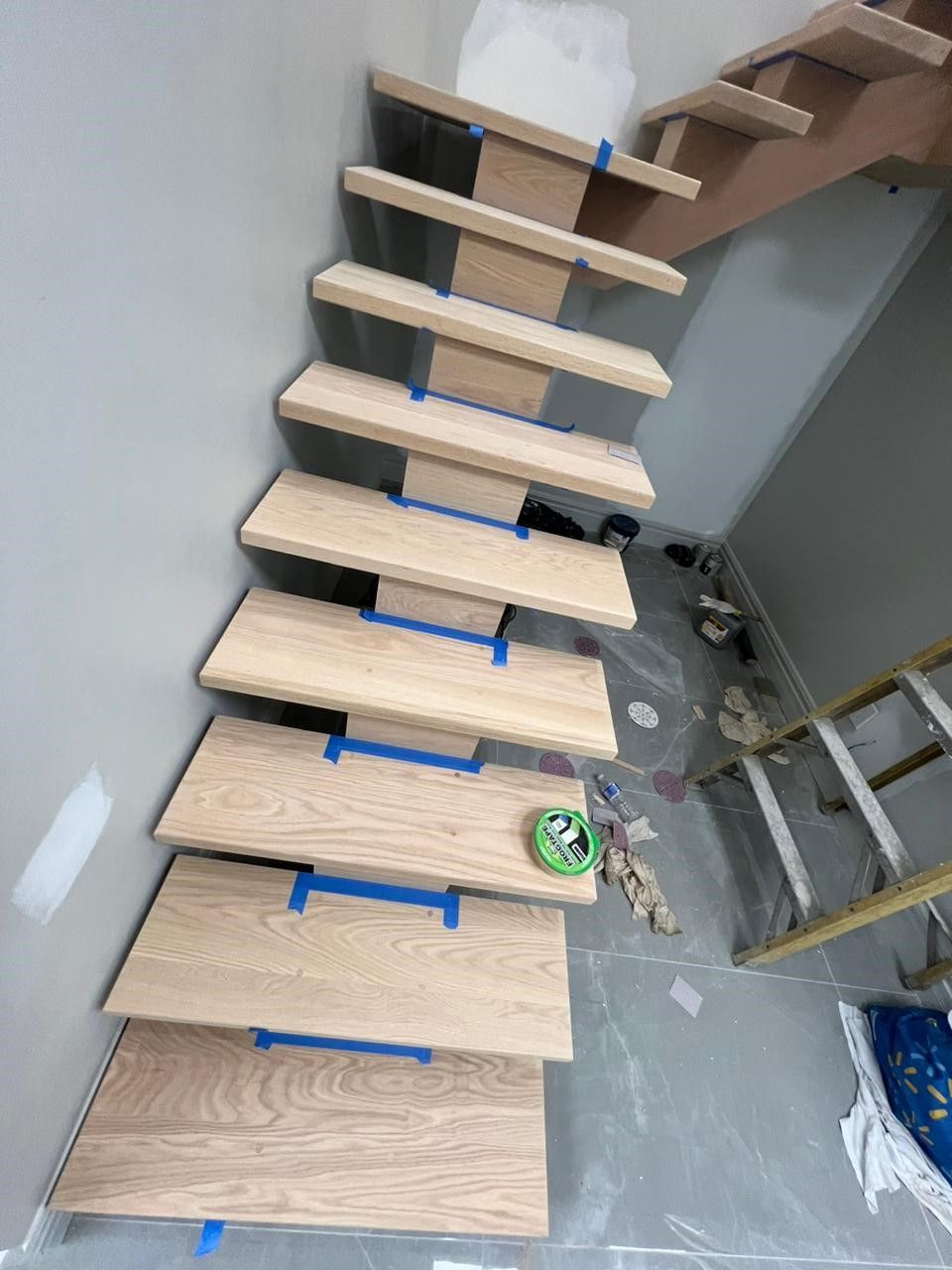 A wooden staircase is being painted in a room.