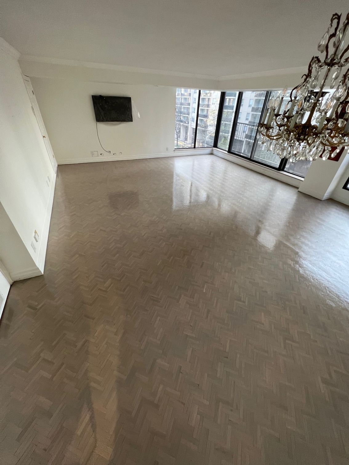 A living room with a chandelier and a flat screen tv on the wall.
