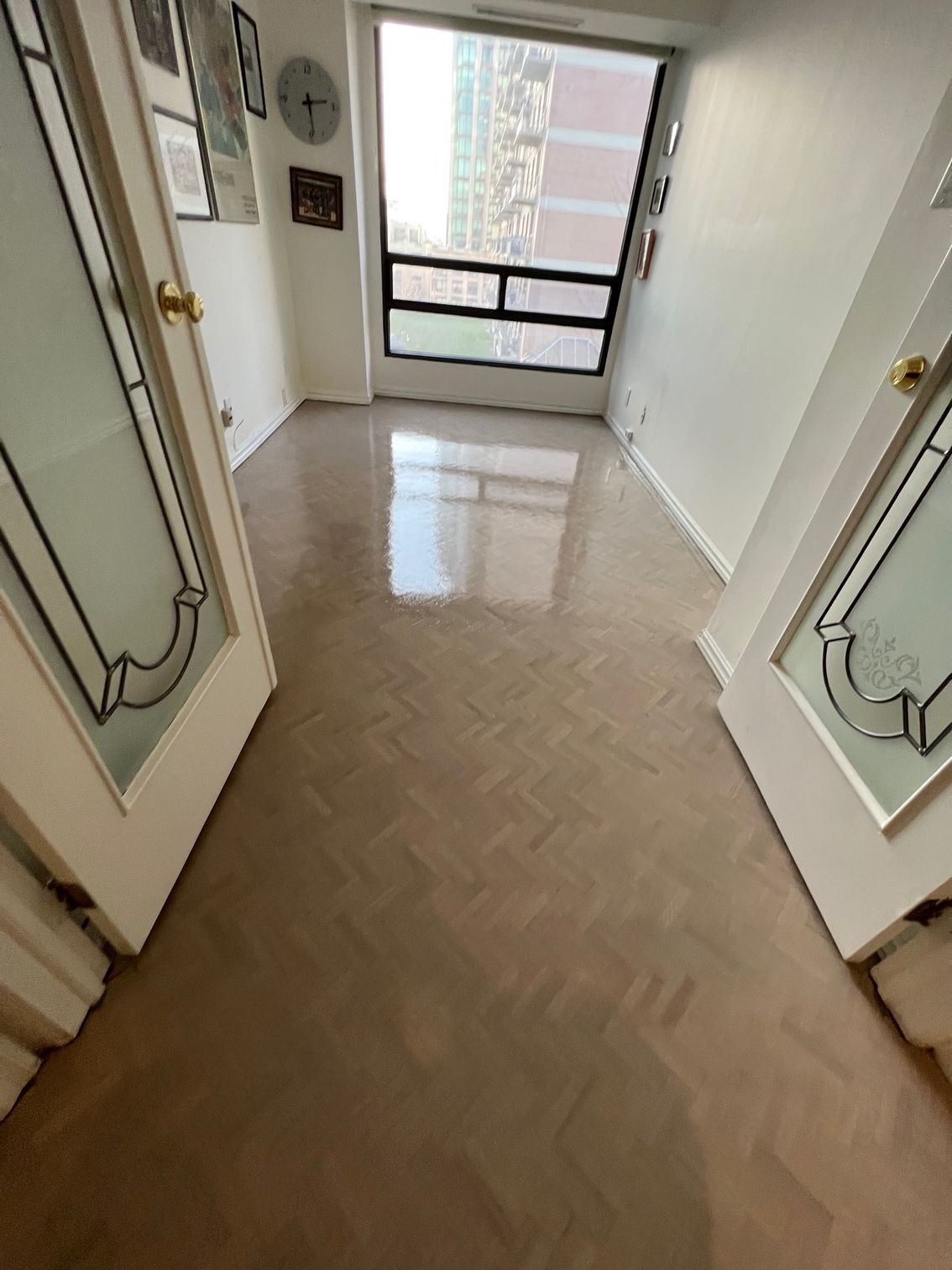a hallway with a clock on the wall and a large window .