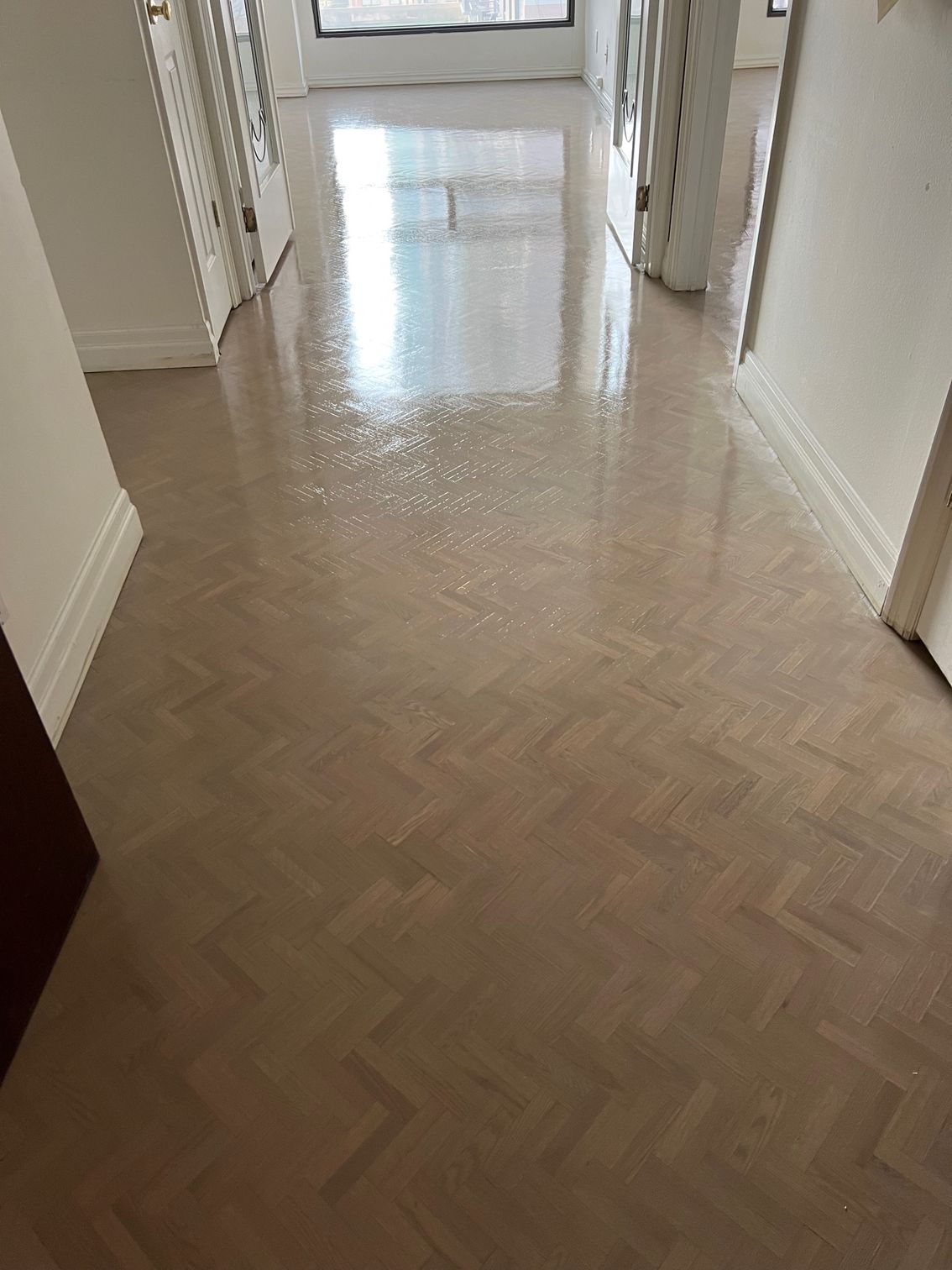 A hallway with a wooden floor and white walls.