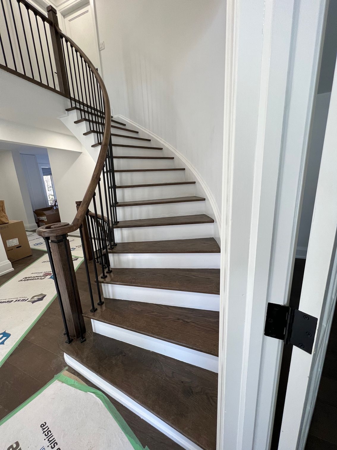 A curved staircase with white steps and a black railing in a house.