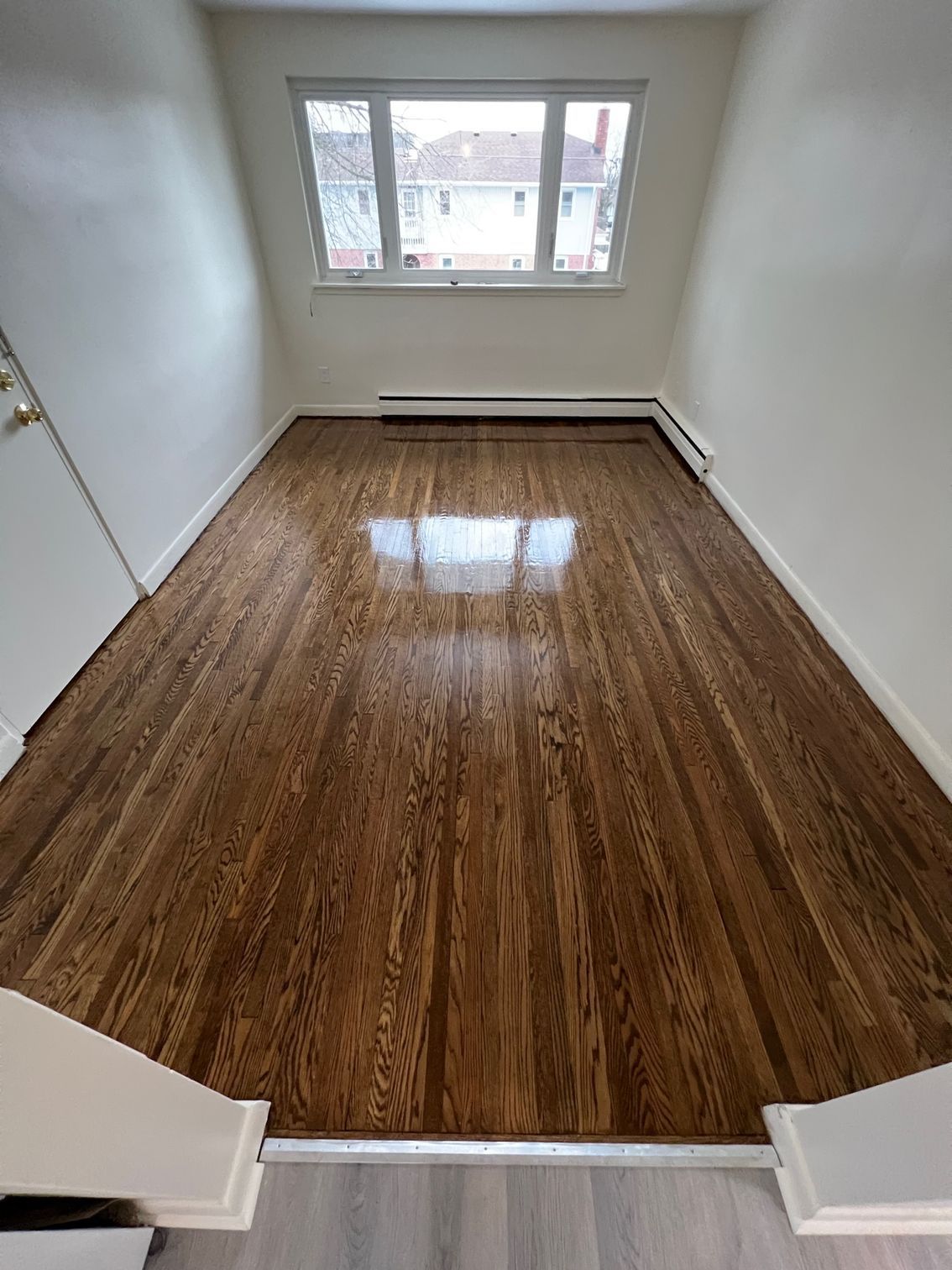 A living room with hardwood floors and a window.