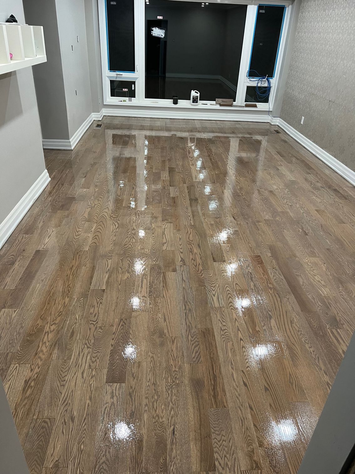 A living room with hardwood floors and a large window.