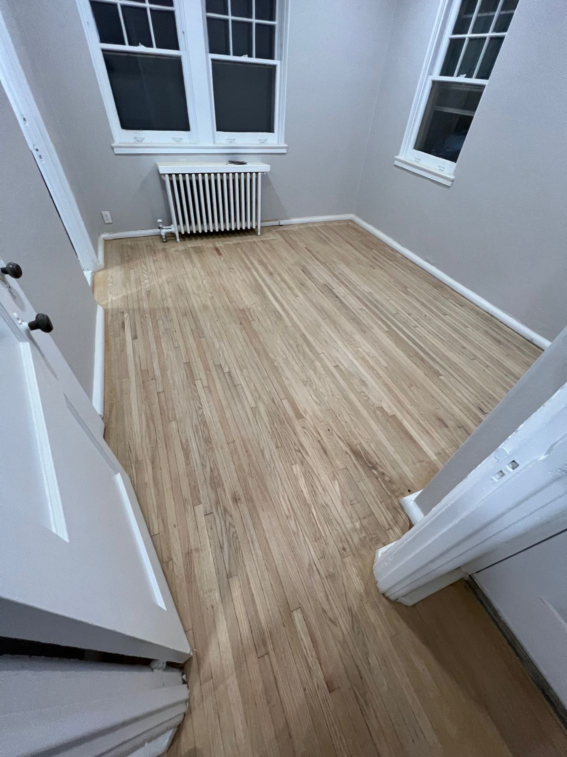 A room with hardwood floors and two windows.