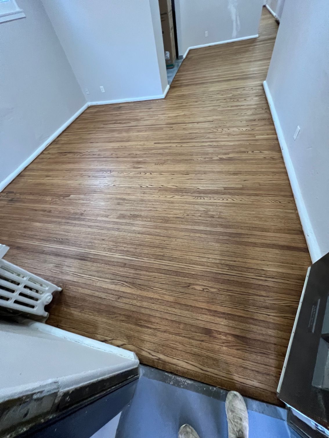 A person is standing on a wooden floor in a room.