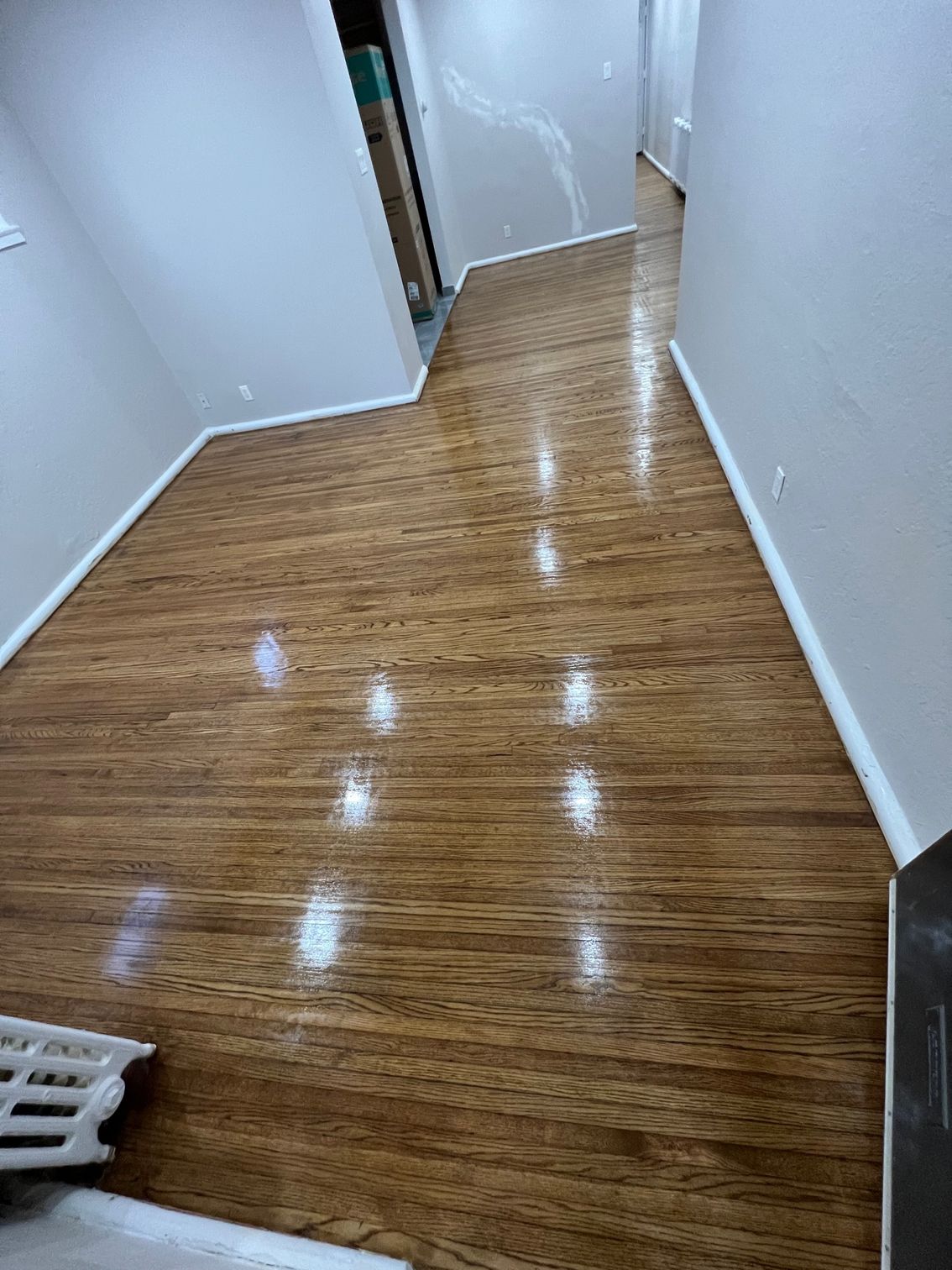 A hallway with a wooden floor and white walls.