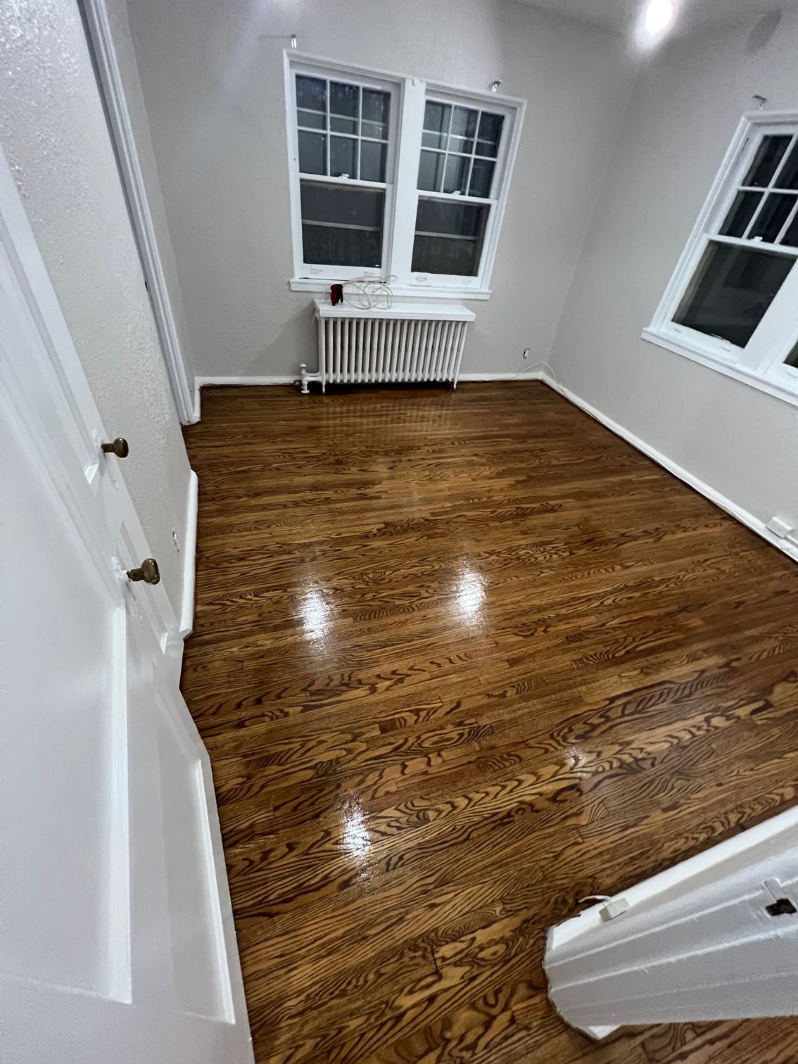 A room with hardwood floors and two windows.