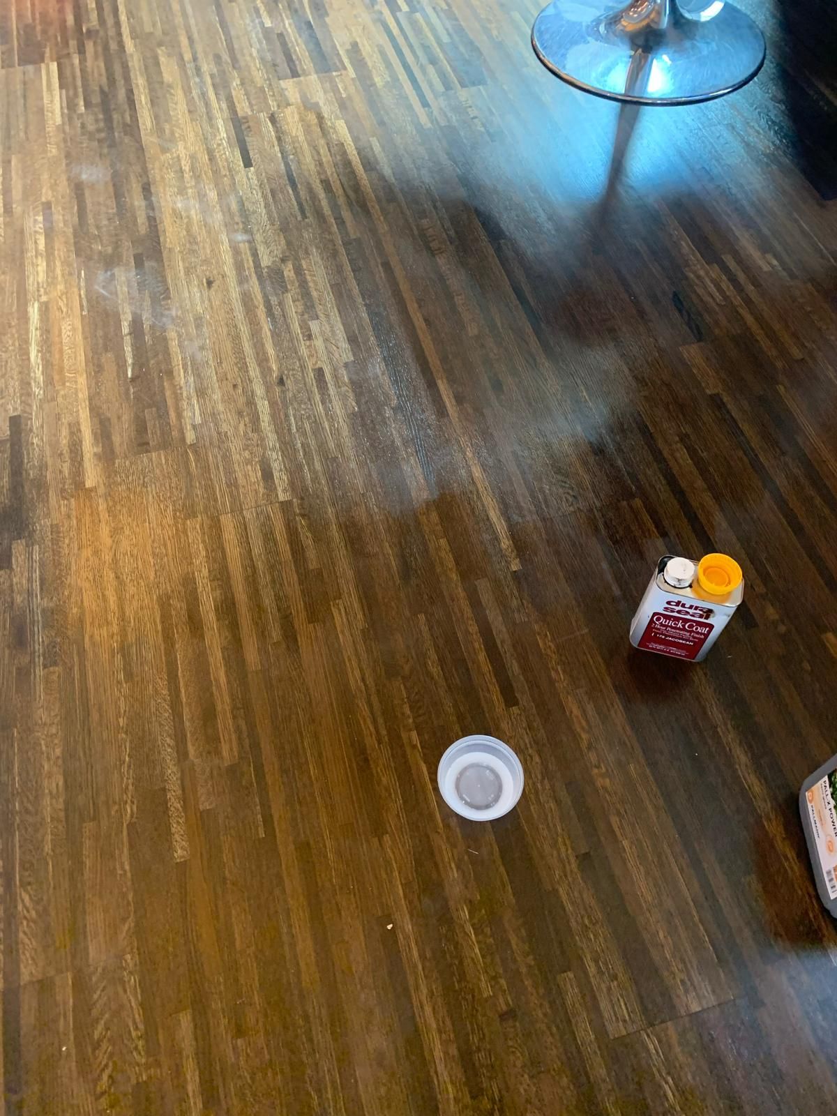 a bottle of milk is sitting on a wooden floor next to a cup .
