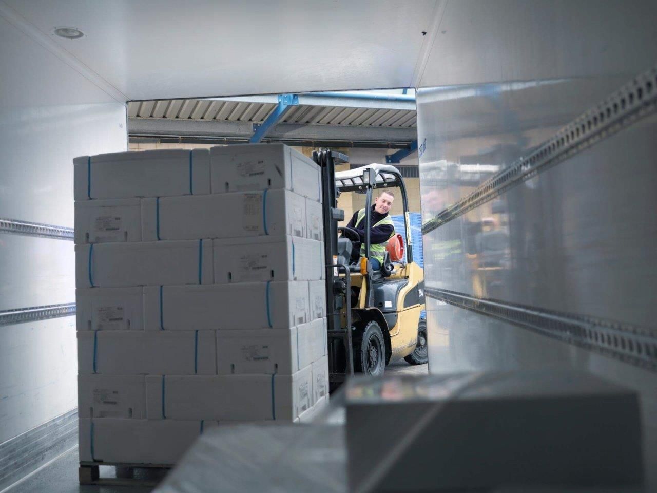 Un uomo sta guidando un carrello elevatore in un magazzino.