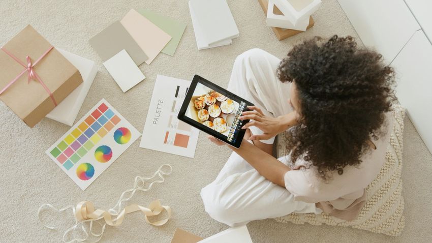 Una donna è seduta sul pavimento e usa un tablet.