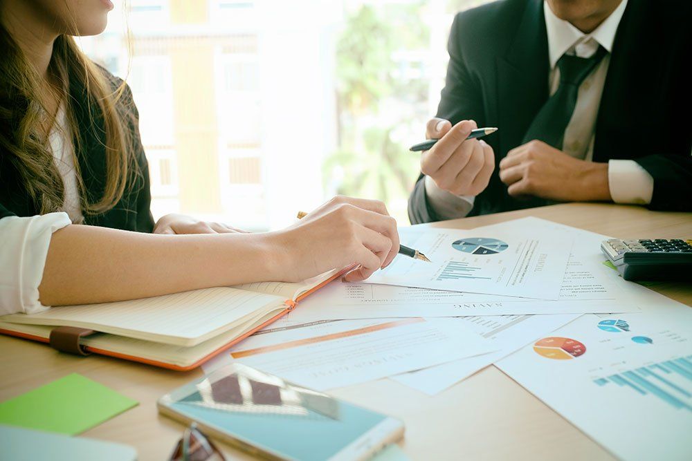 A man and a woman are sitting at a table looking at papers.
