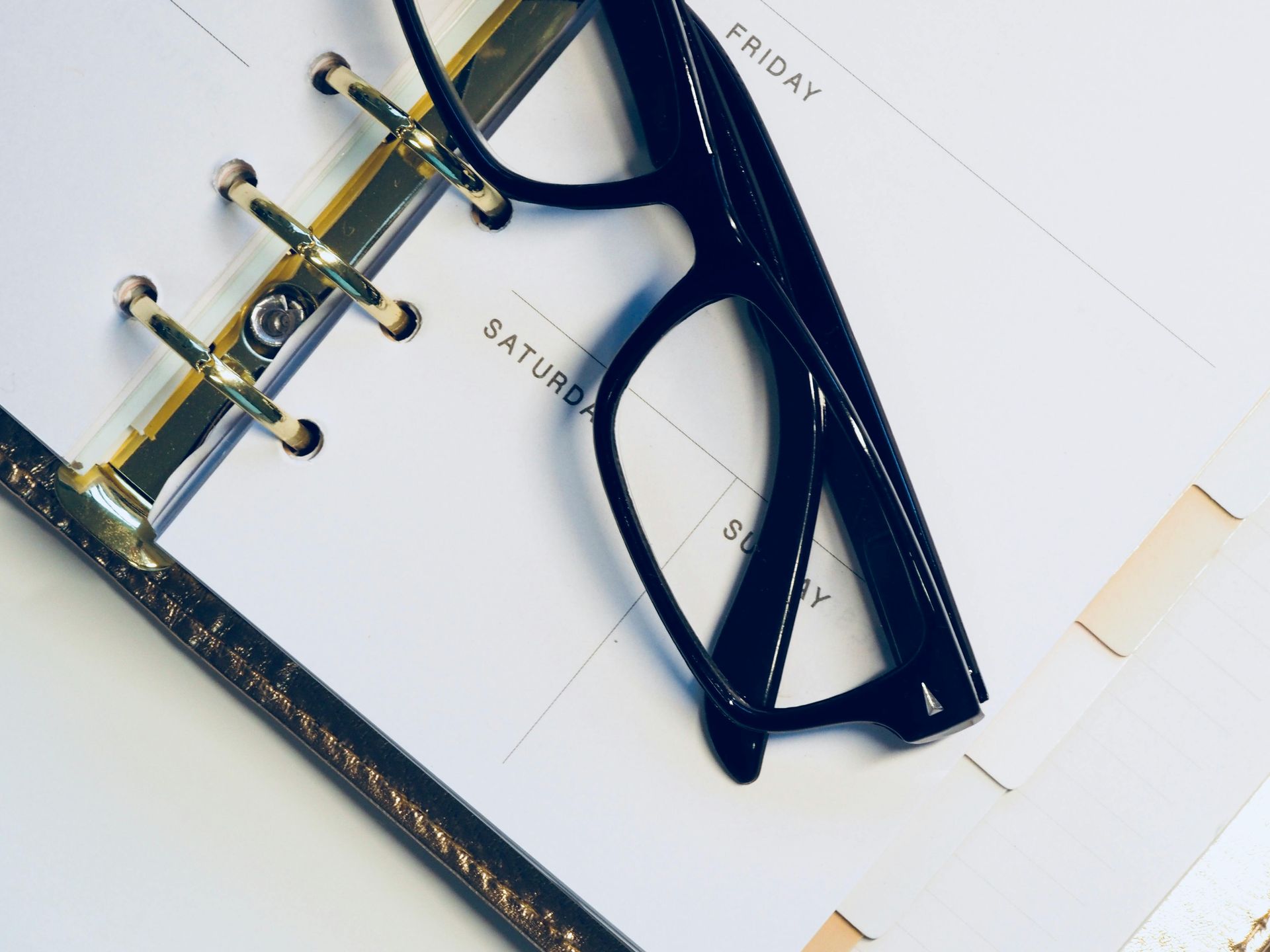 A pair of glasses laying on top of a calendar