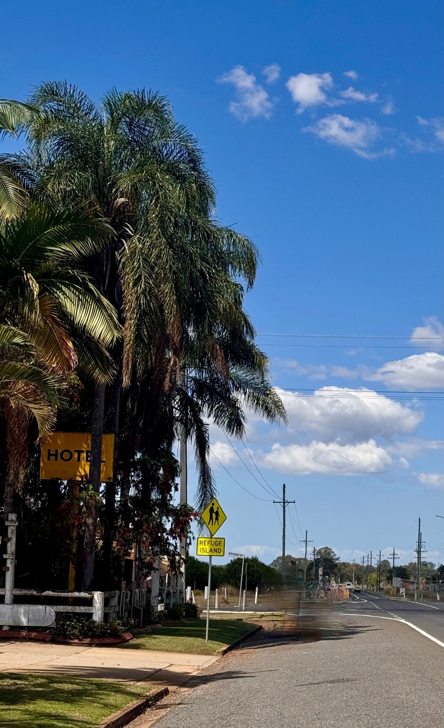 Palm trees line a road on a sunny day with a blue sky and some clouds. — Gin Gin Domestic Water Supplies in South Kolan, QLD