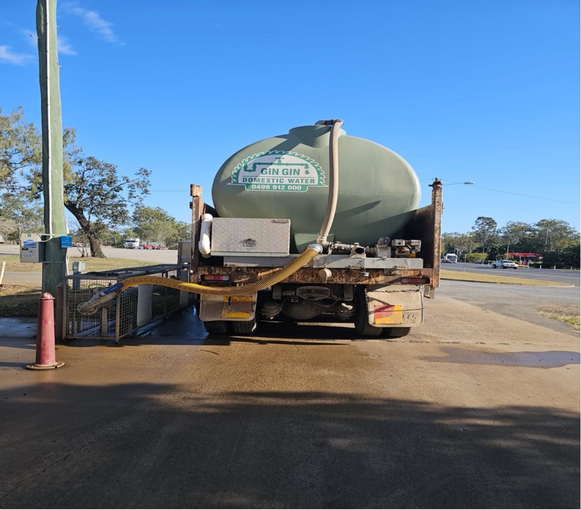 Water tanker truck parked, discharging water onto concrete near a road. — Gin Gin Domestic Water Supplies in Wallaville, QLD