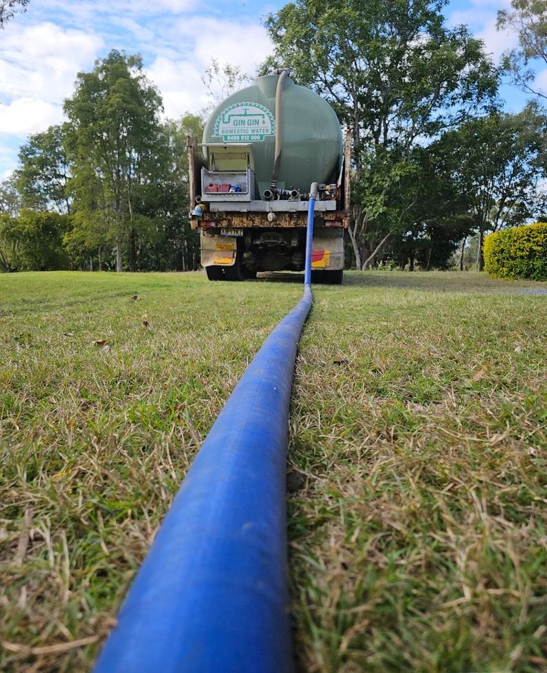 A person hoses a septic tank. A truck is parked on grass under a blue sky. — Gin Gin Domestic Water Supplies in Wallaville, QLD