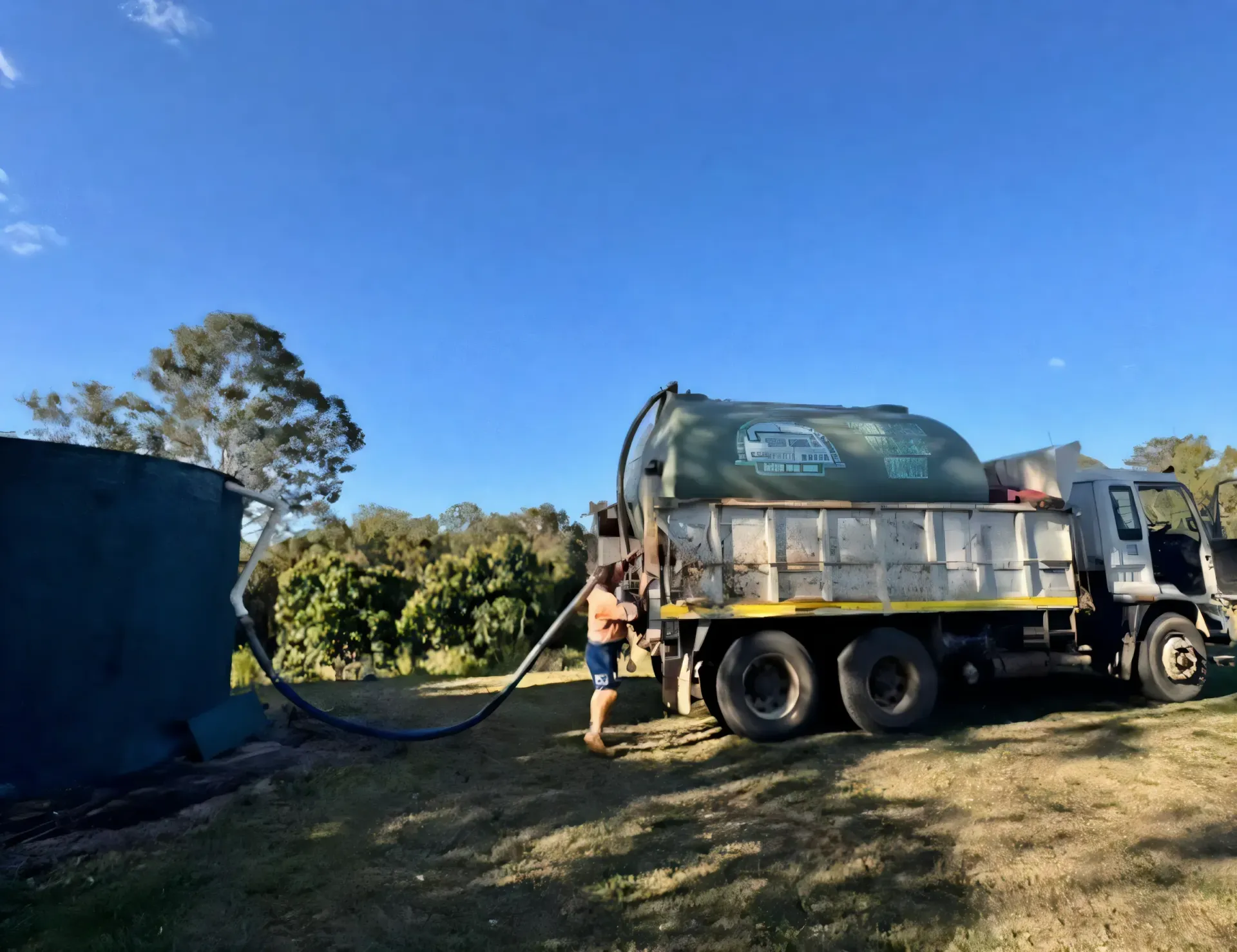 Blue hose extending from a water tanker truck parked on a grassy lawn. — Gin Gin Domestic Water Supplies in Wallaville, QLD