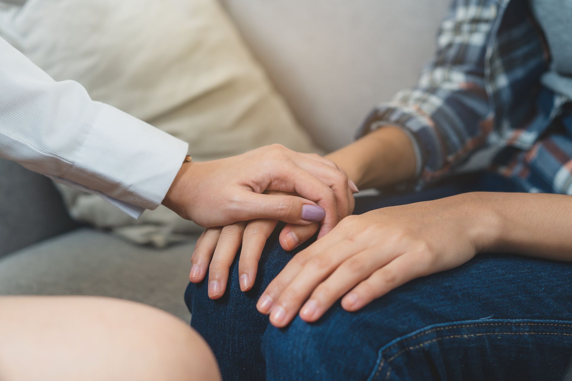 Two people holding hands on a couch in a supportive gesture