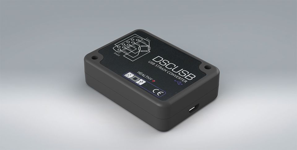 Small, black DSCUSB strain gauge to USB converter on a plain grey backdrop with clear readings on the screen.