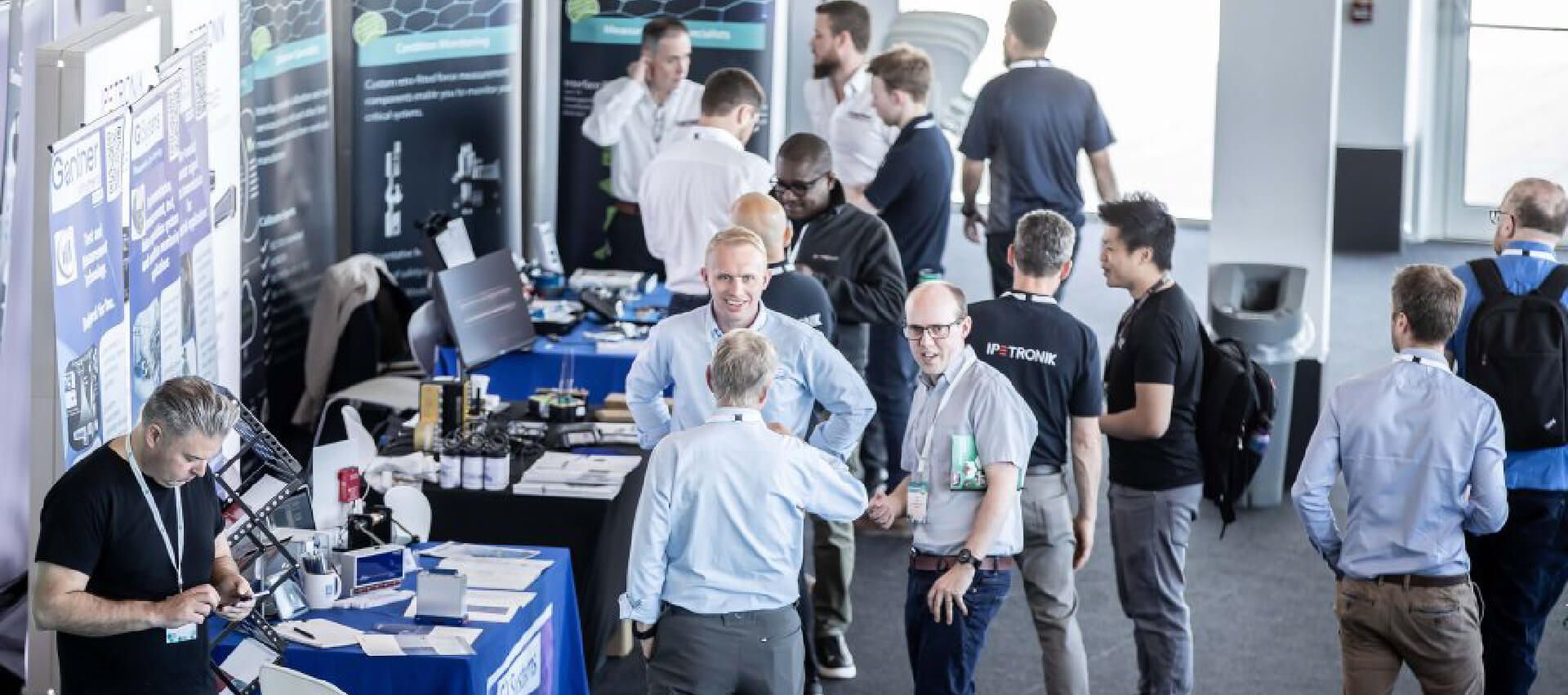 Picture of stands and people talking at the Instrumentation, Analysis & Testing Exhibition hosted by the Engineering Integrity Society in the Silverstone Wing.
