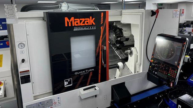 A mazak machine is sitting in a room next to a computer.