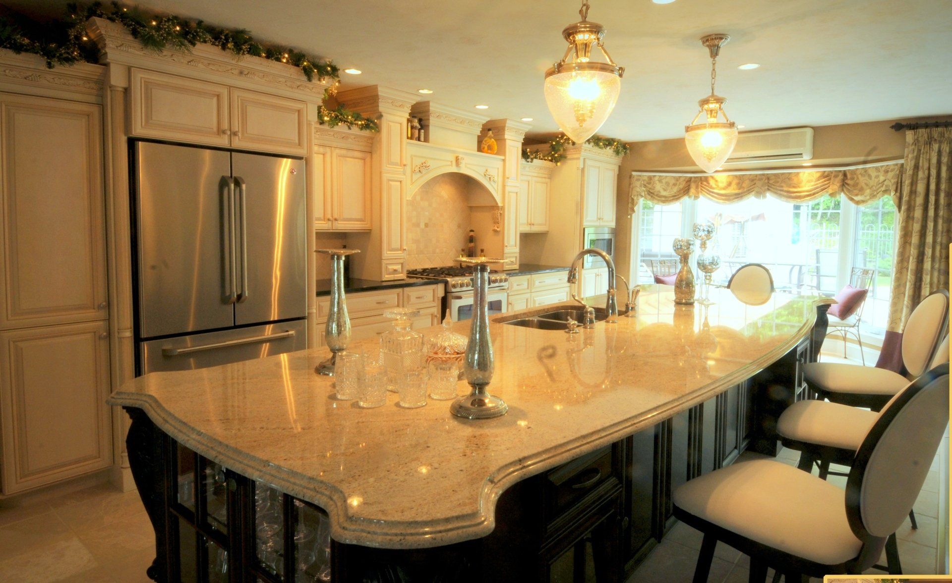 Upscale kitchen with large island, granite countertops, stainless steel appliances, and pendant lights.