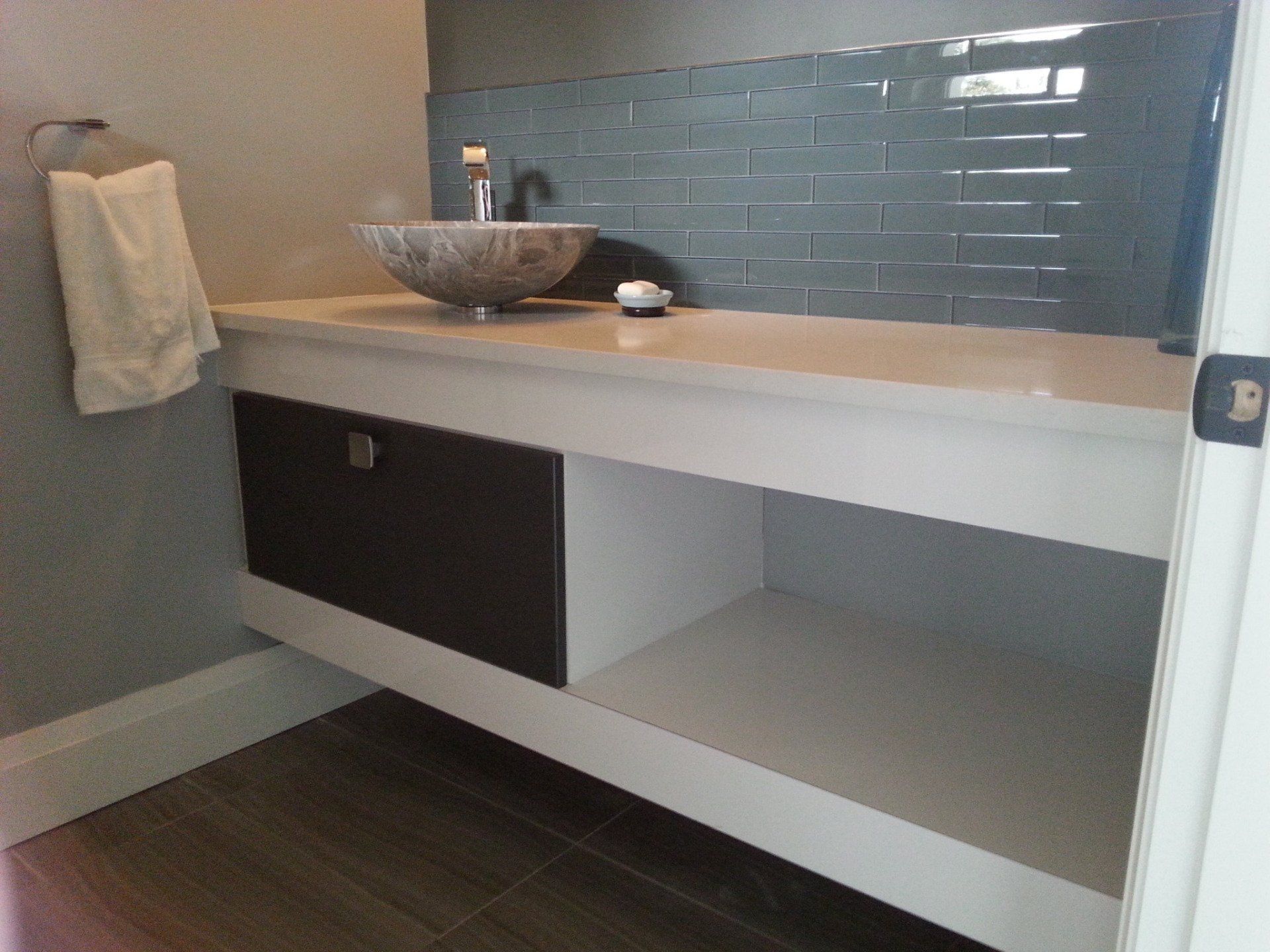 Modern bathroom with a floating vanity, vessel sink, and dark accent cabinet; gray tile backsplash.