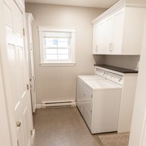 Laundry room with white cabinets, washer/dryer, and small window.