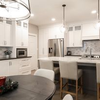 Modern white kitchen with dining area and stainless steel appliances.