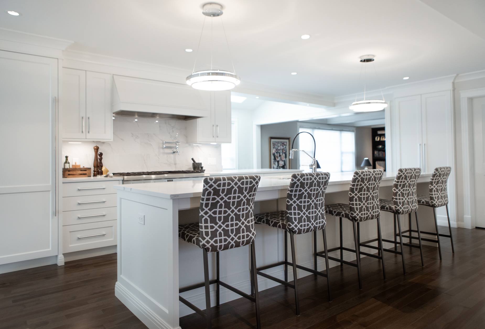 White kitchen with island bar and patterned stools.