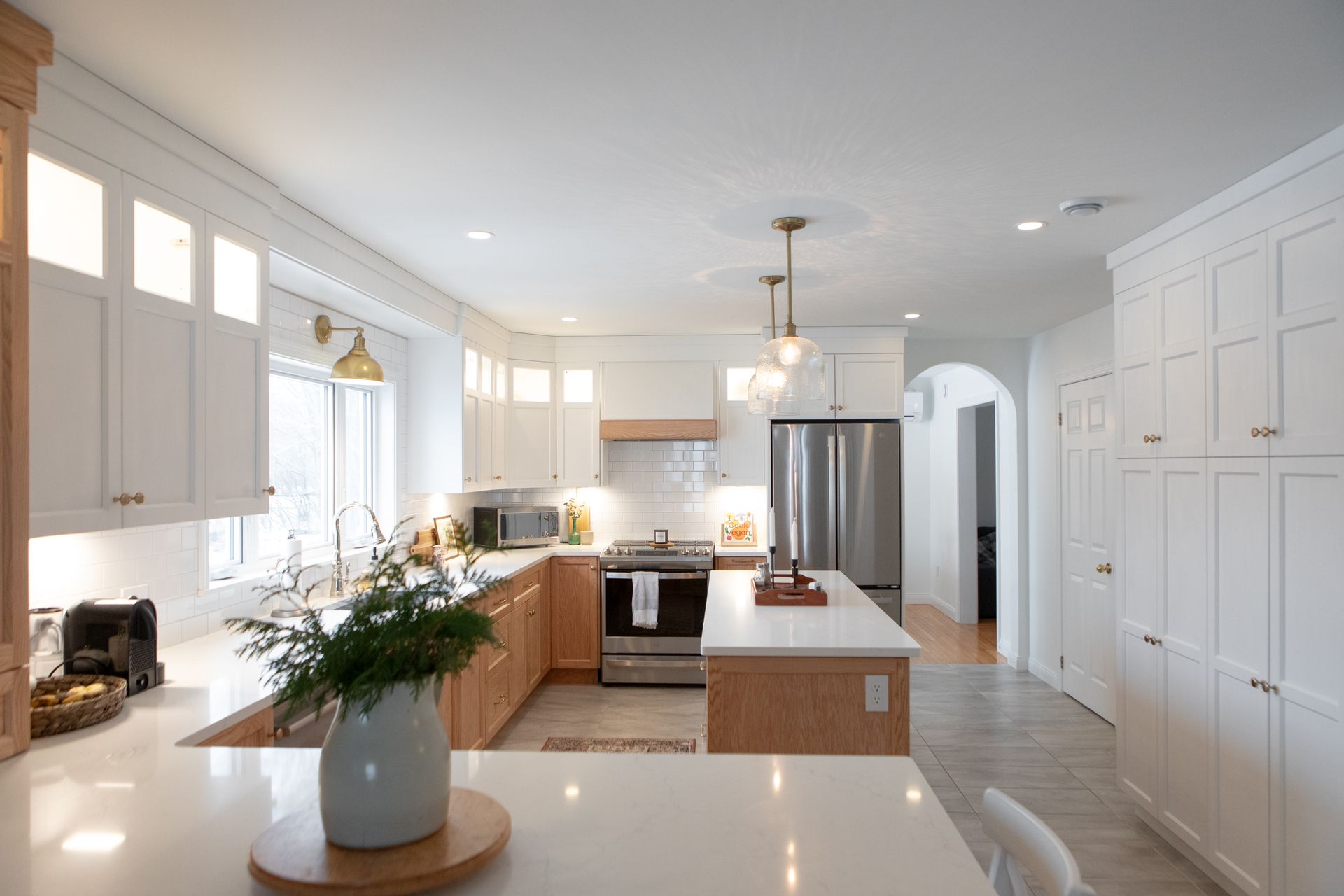 Bright kitchen with white cabinets, wood accents, island, stainless steel appliances.