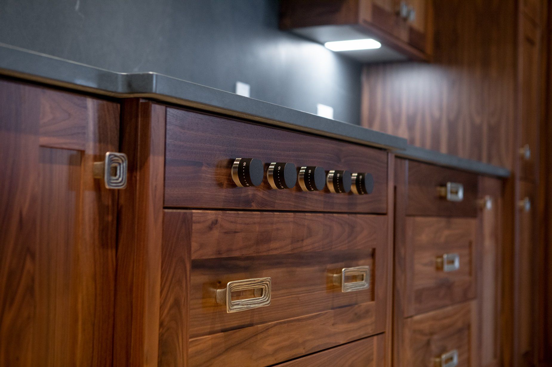 Wooden kitchen cabinets with contrasting dark countertop and hardware.