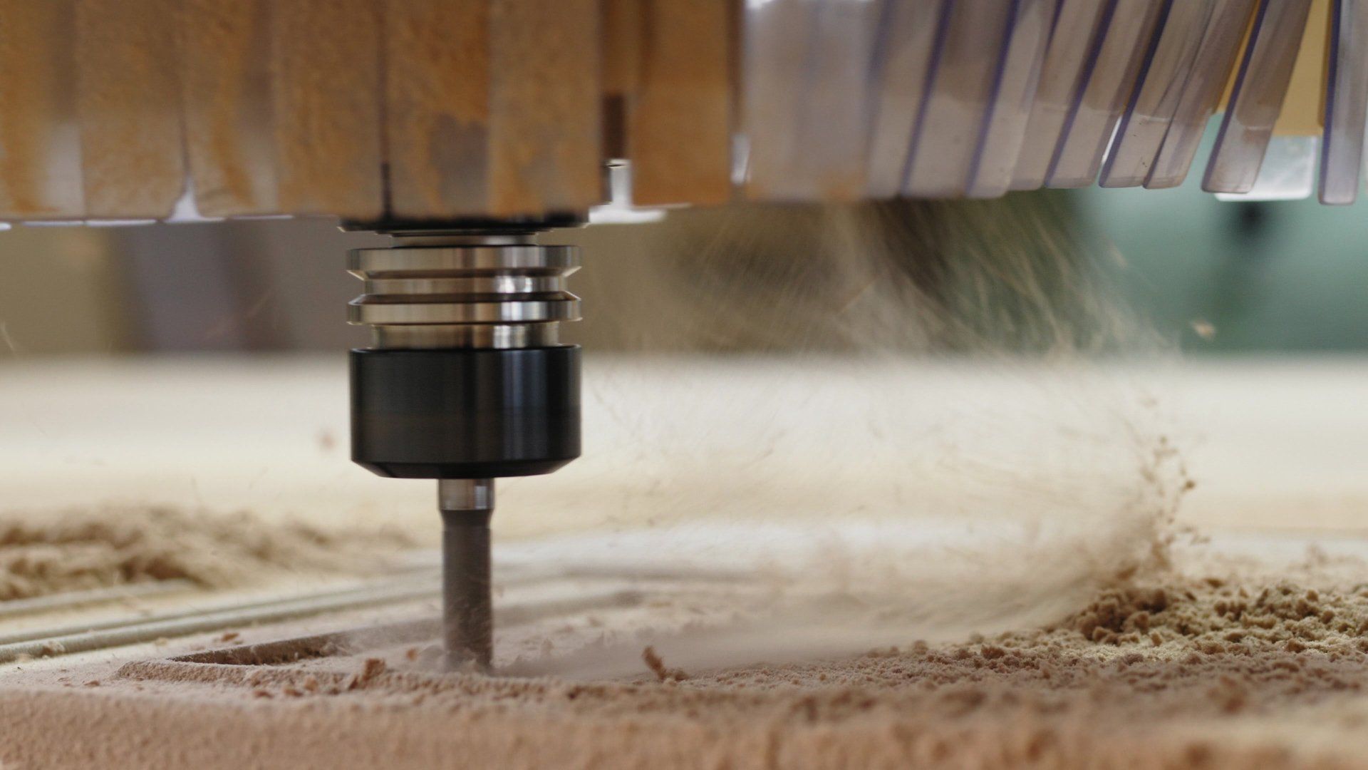 CNC router cutting wood, creating sawdust.