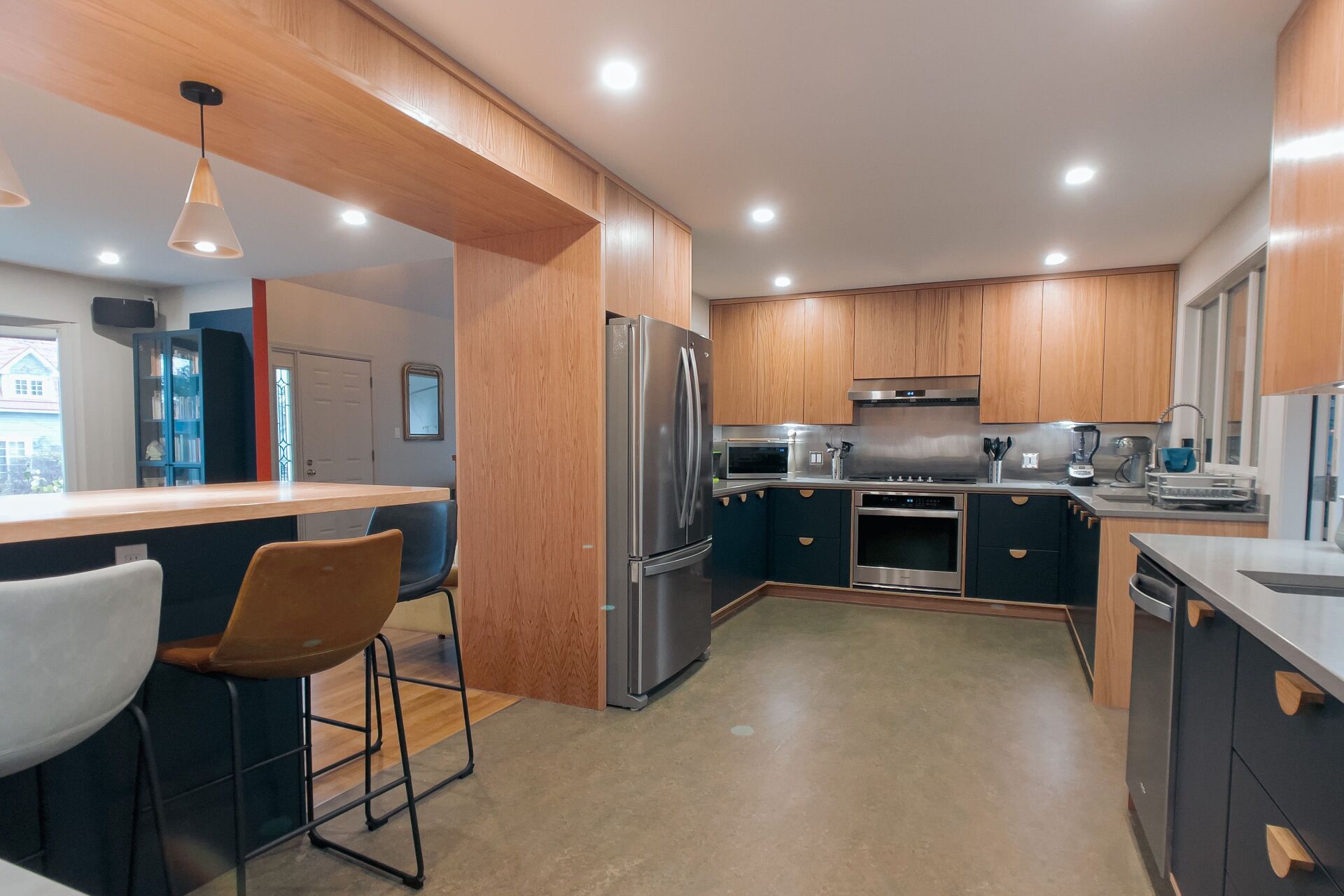 Modern kitchen with wood cabinets, stainless steel appliances, and a dark blue island.